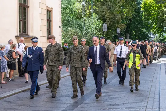 Parada wojskowa z udziałem żołnierzy i cywilów na ulicy.