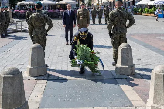 Żołnierz składa wieniec na pamiątkowej tablicy podczas ceremonii wojskowej.