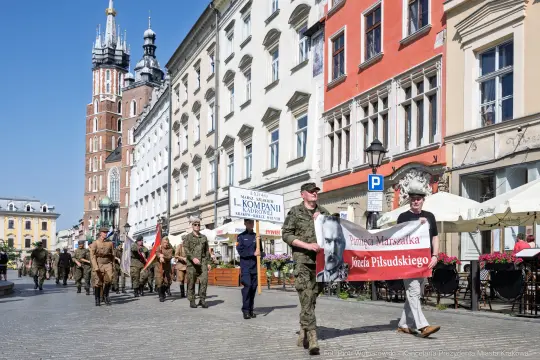 Marsz z flagami i transparentem upamiętniającym Józefa Piłsudskiego na krakowskim rynku.