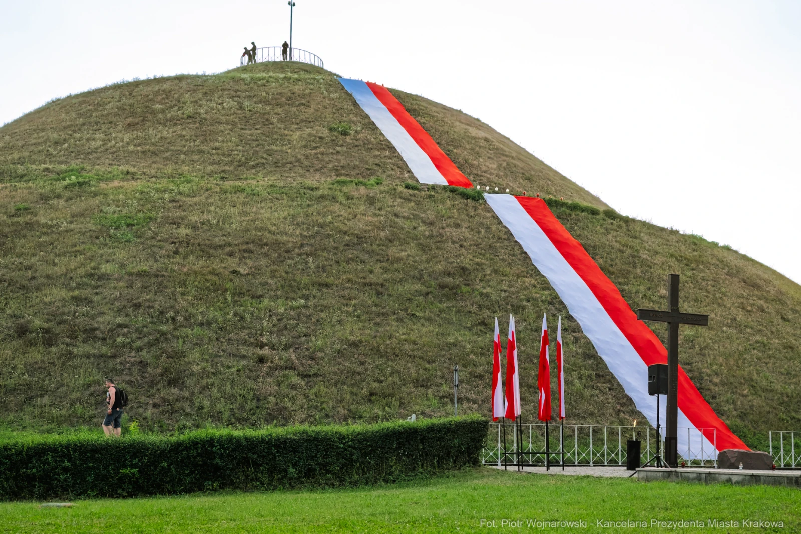 Kopiec z biało-czerwoną flagą, obok krzyż i flagi Polski.  Autor: Piotr Wojnarowski