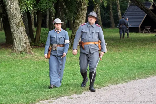 Dwójka żołnierzy w mundurach historycznych spaceruje po terenie leśnym.