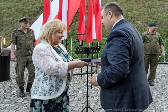 Wręczenie nagrody w obecności żołnierzy i flag narodowych.
