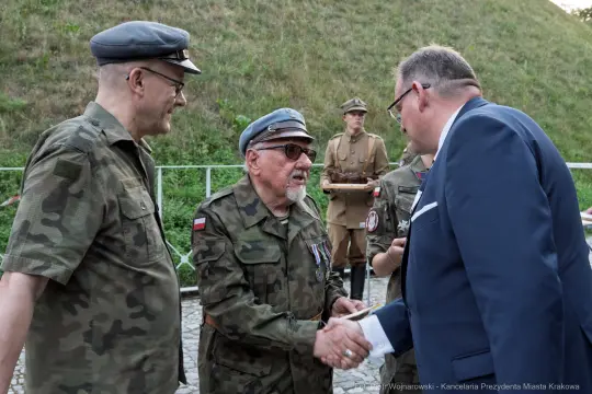 Spotkanie dwóch mężczyzn w mundurach wojskowych z osobą w garniturze.
