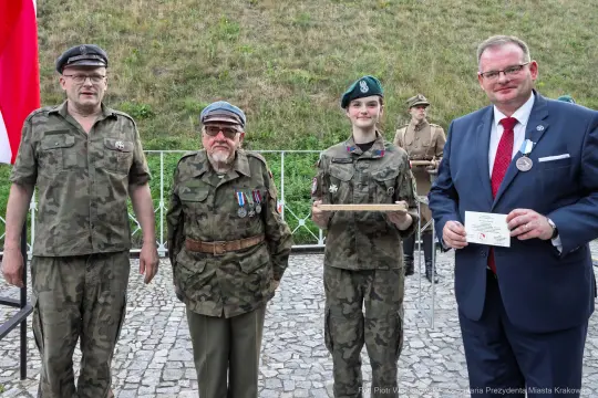 Czterech mężczyzn i jedna kobieta w mundurach wojskowych, trzymający nagrody i odznaczenia.