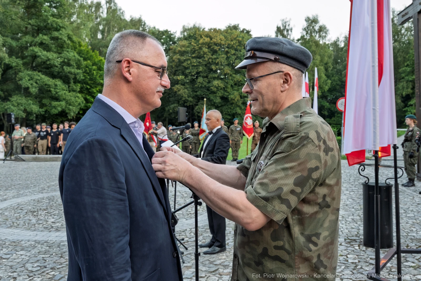 Ceremonia wręczenia odznaczenia wojskowego. Mężczyzna w mundurze przypina medal do marynarki innego mężczyzny.  Autor: Piotr Wojnarowski