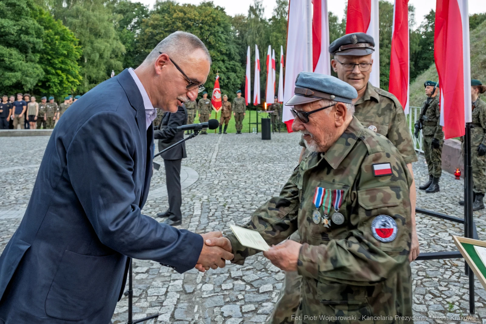 Wręczenie odznaczeń wojskowych podczas ceremonii z flagami Polski w tle.  Autor: Piotr Wojnarowski