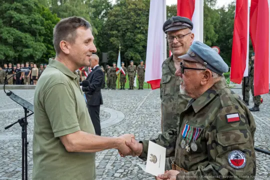 Uroczystość wręczenia odznaczeń wojskowych z udziałem żołnierzy i flag narodowych.