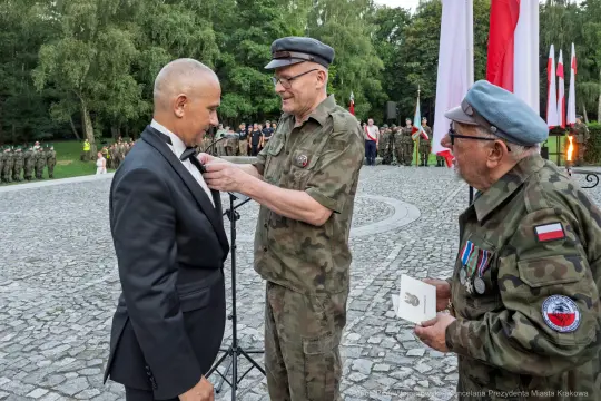 Ceremonia wręczenia odznaczenia wojskowego w plenerze.