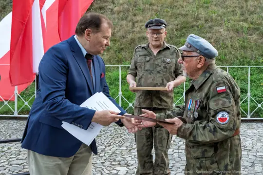 Wręczenie odznaczeń w obecności flagi Polski.