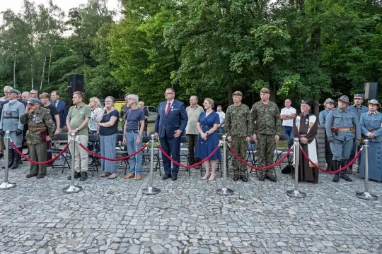 Uczestnicy wydarzenia historycznego w strojach z różnych epok, stojący w rzędzie.