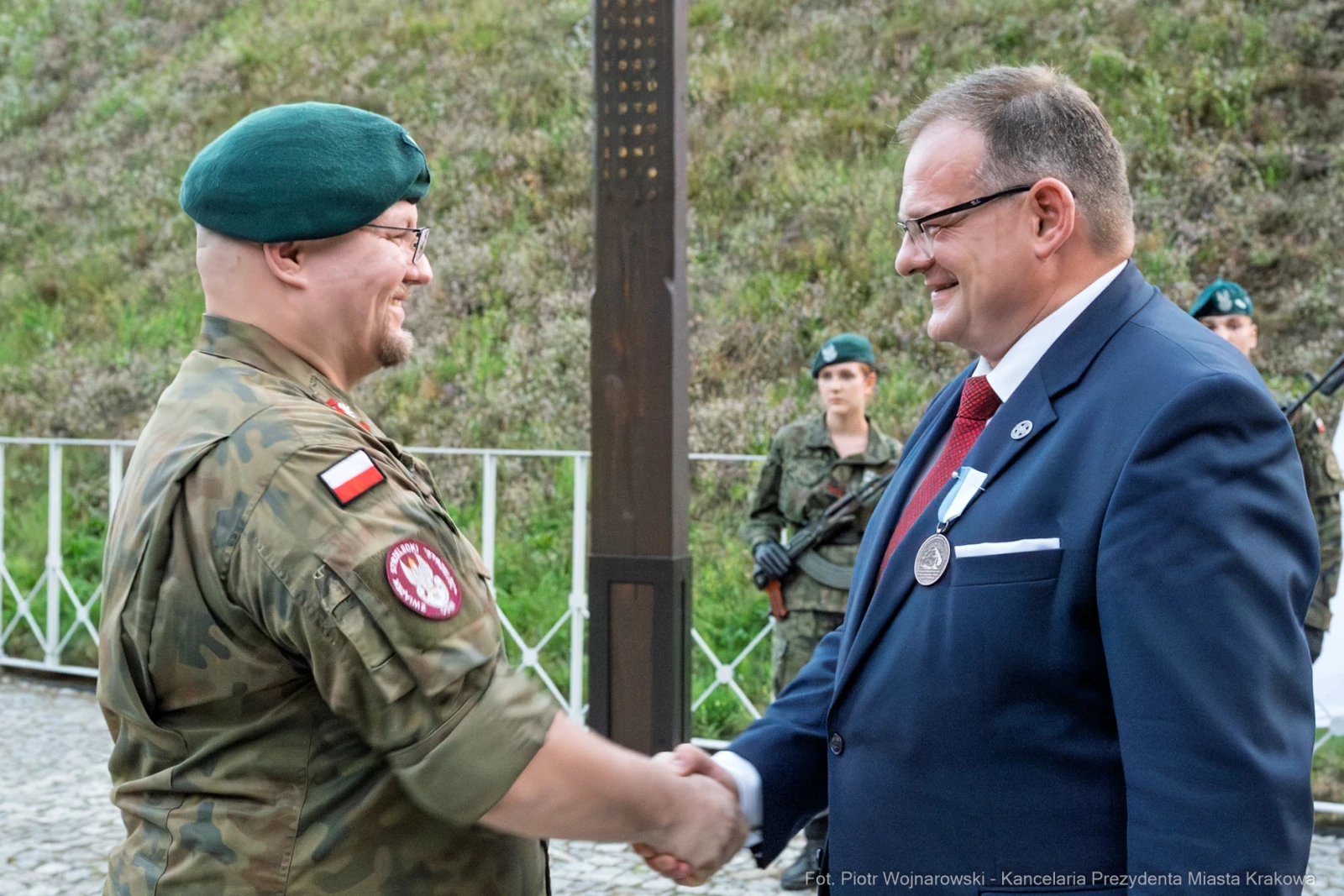 Dwaj mężczyźni w mundurze wojskowym i garniturze uścisną ręce podczas ceremonii.  Autor: Piotr Wojnarowski