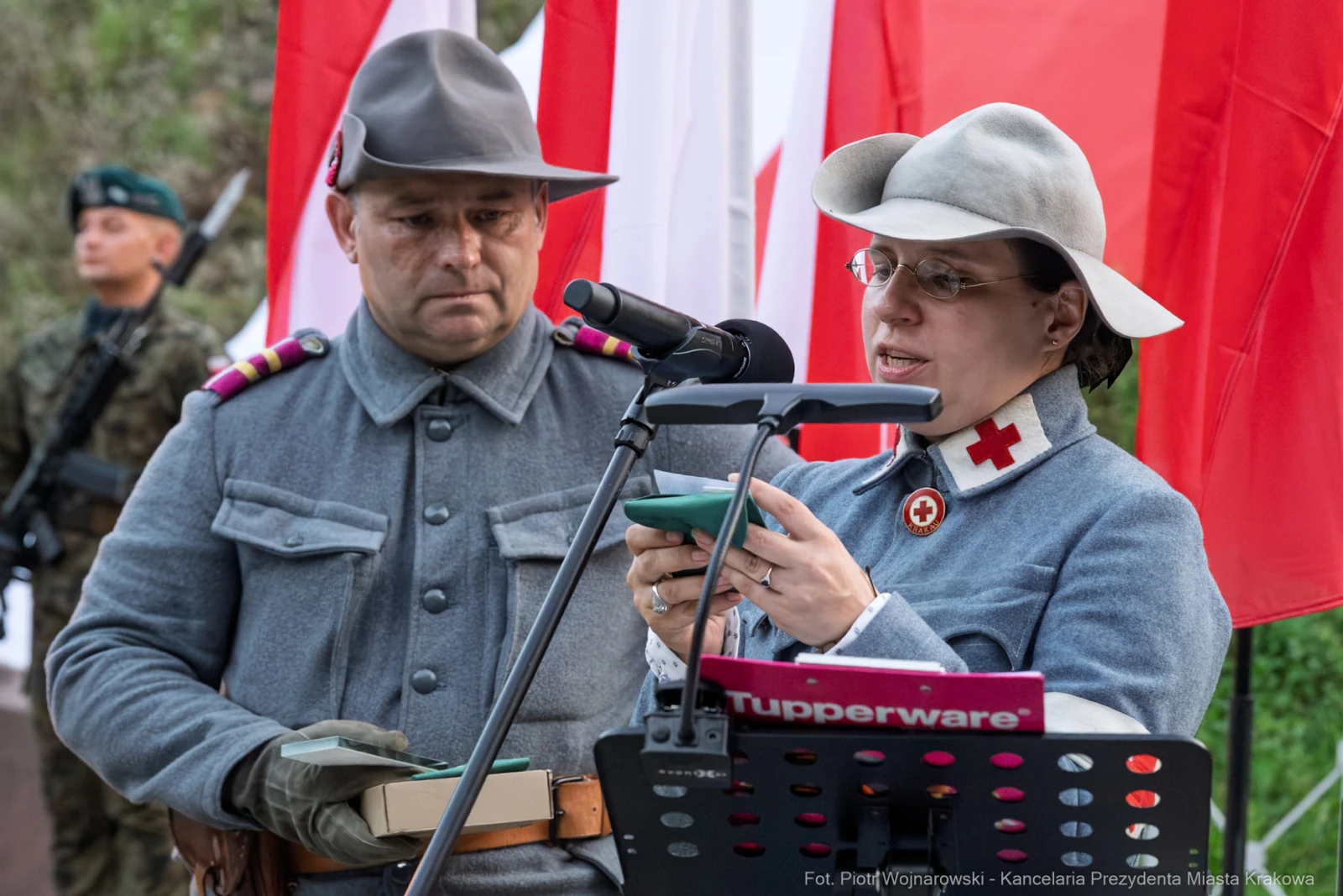 Mężczyzna i kobieta w mundurach podczas uroczystości, obok flagi Polski.  Autor: Piotr Wojnarowski