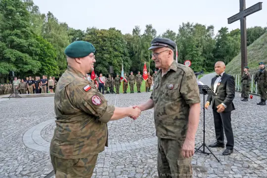 Dwaj żołnierze w mundurach podają sobie ręce podczas ceremonii wojskowej.