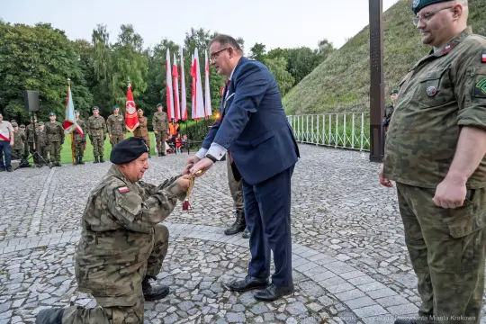 Ceremonia wręczenia odznaczeń wojskowych w obecności żołnierzy i flag narodowych.