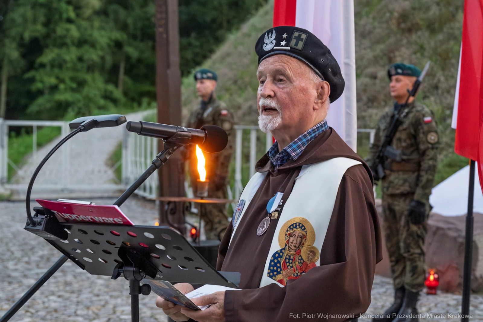 Starszy mężczyzna w mundurze wygłasza przemówienie, w tle flagi i żołnierze.  Autor: Piotr Wojnarowski