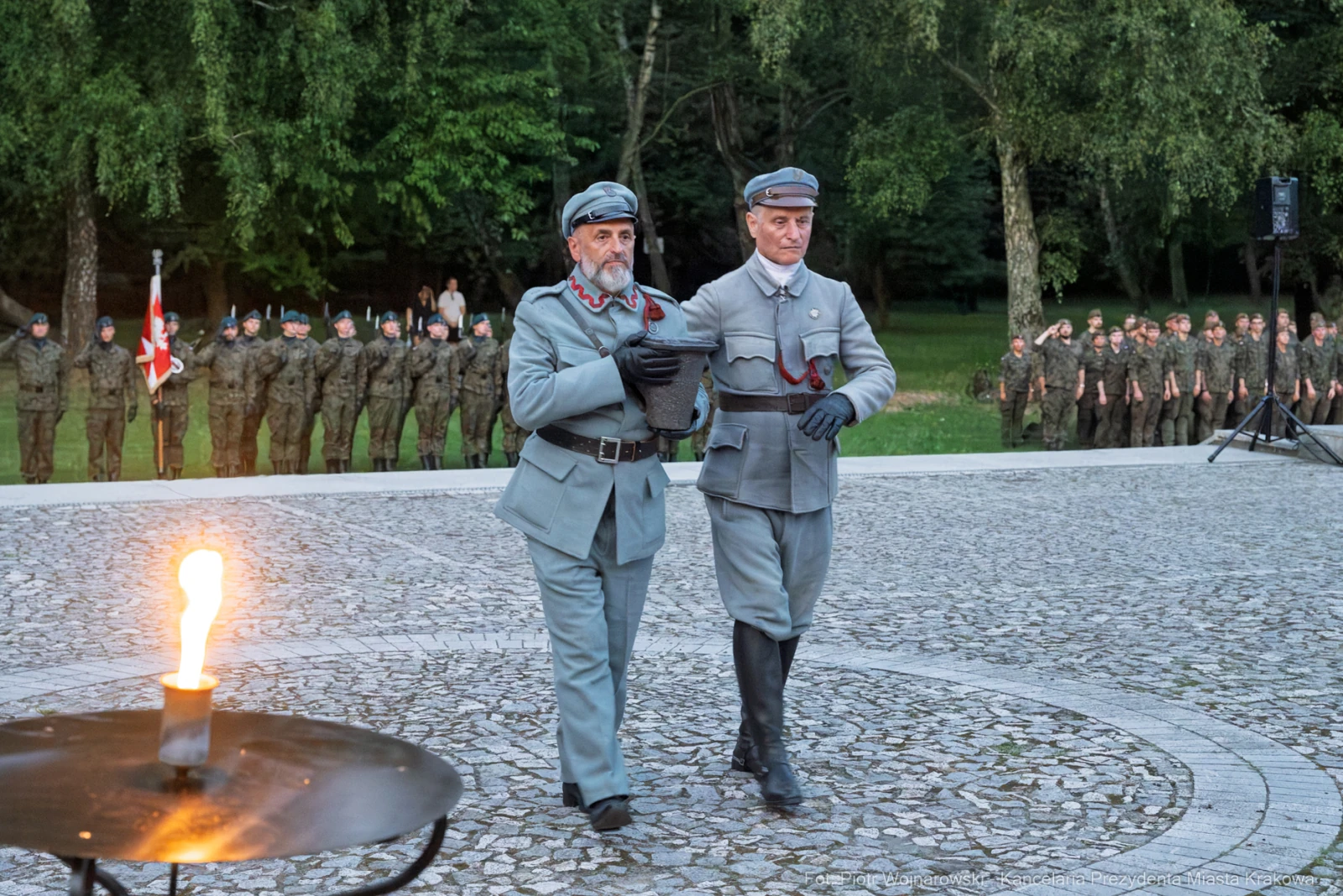 Dwaj mężczyźni w mundurach historycznych, obok żołnierze w tle, ceremonia z ogniem.  Autor: Piotr Wojnarowski