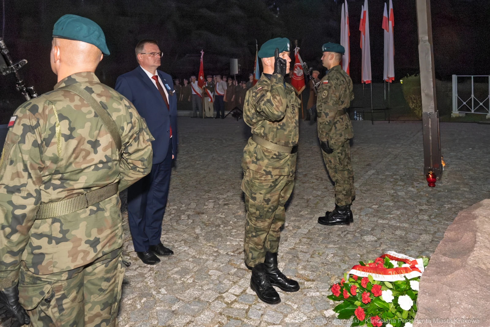 Ceremonia wojskowa z żołnierzami w mundurach i przedstawicielem władz, z wieńcem na ziemi.  Autor: Piotr Wojnarowski