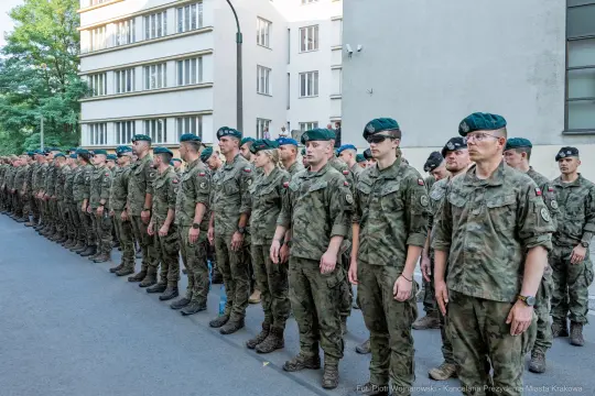 Żołnierze w mundurach stoją w szeregu podczas ceremonii wojskowej.