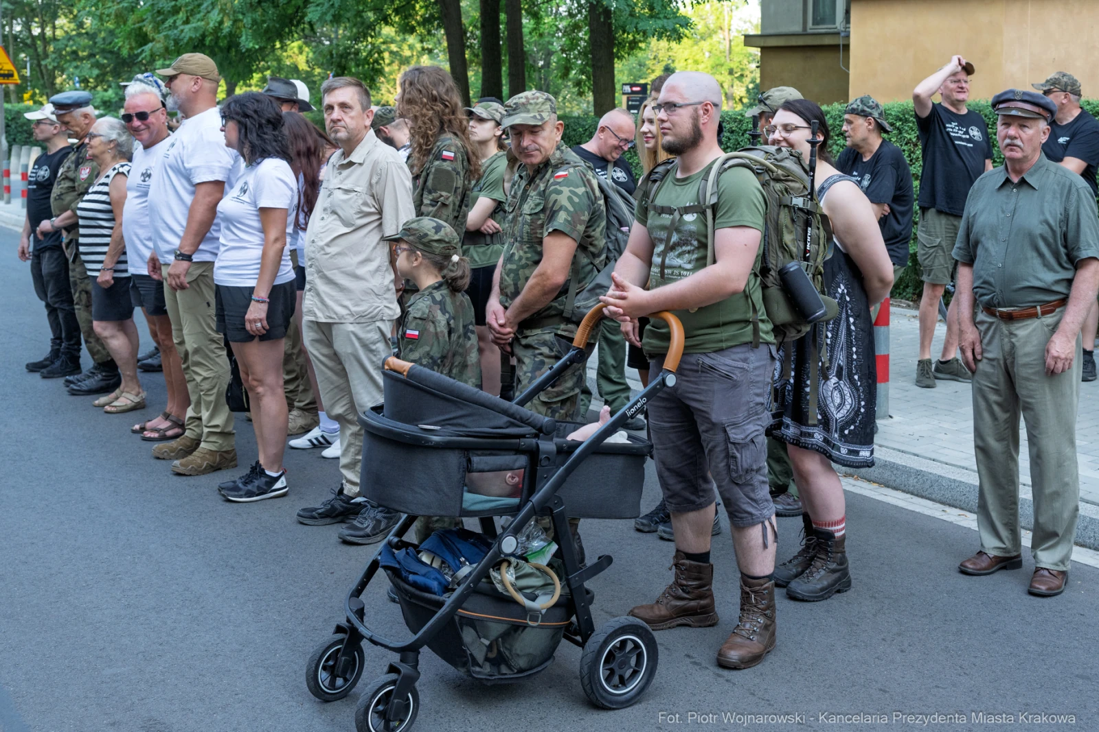 Grupa ludzi w mundurach wojskowych i cywilnych, niektórzy z dziećmi w wózkach.  Autor: Piotr Wojnarowski