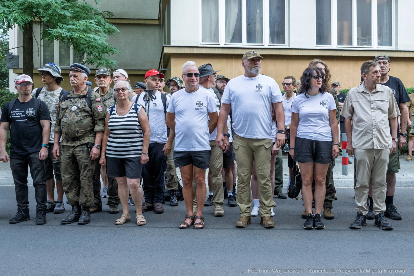 Grupa ludzi w koszulkach, stojących w szeregu na ulicy, w różnorodnych strojach.  Autor: Piotr Wojnarowski