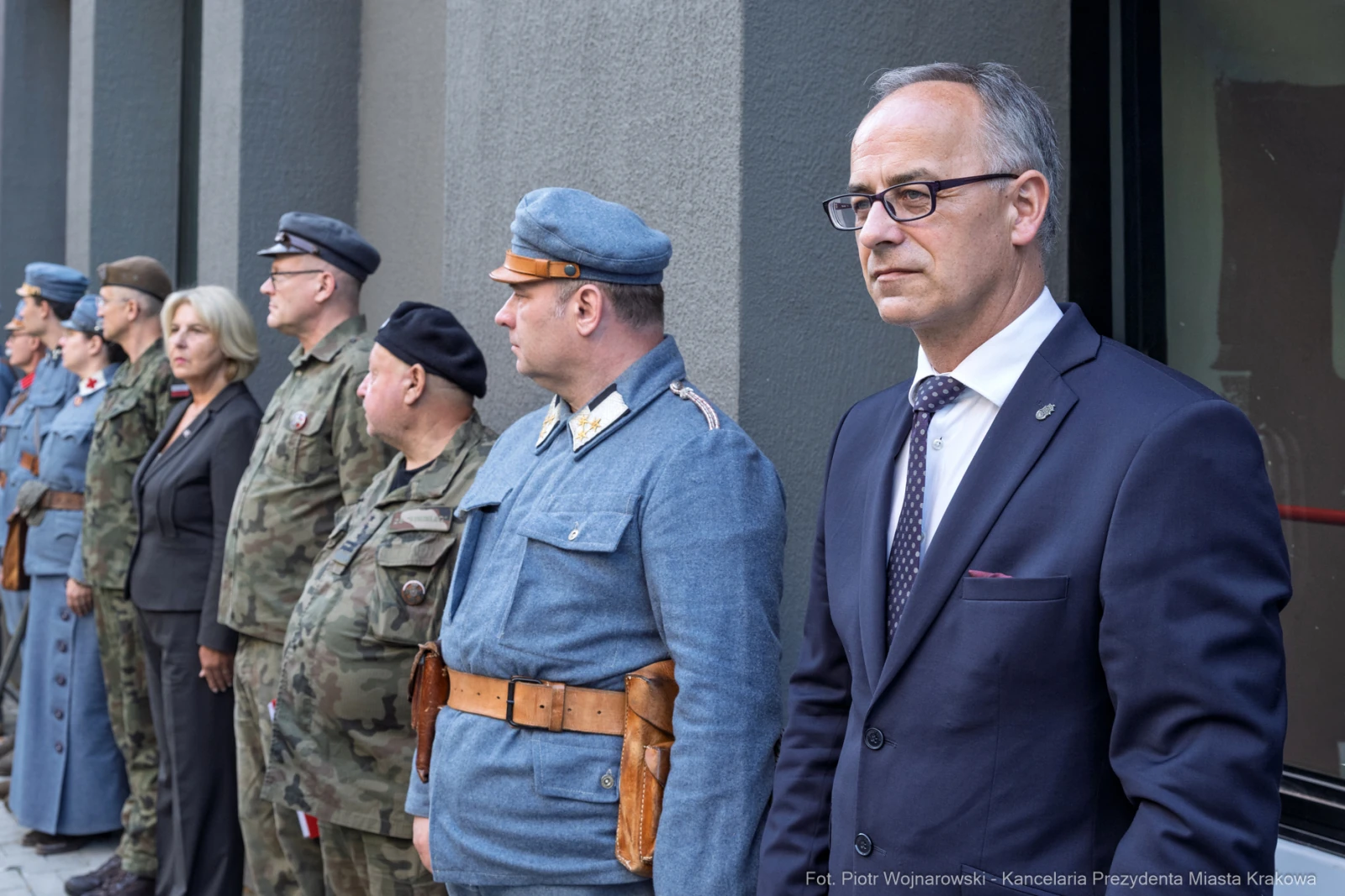 Grupa osób w mundurach i eleganckich strojach, stojących w szeregu podczas uroczystości.  Autor: Piotr Wojnarowski