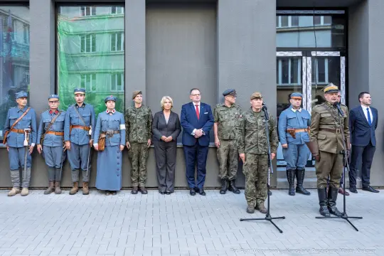 Uczestnicy ceremonii w mundurach historycznych i współczesnych, stojący w szeregu.