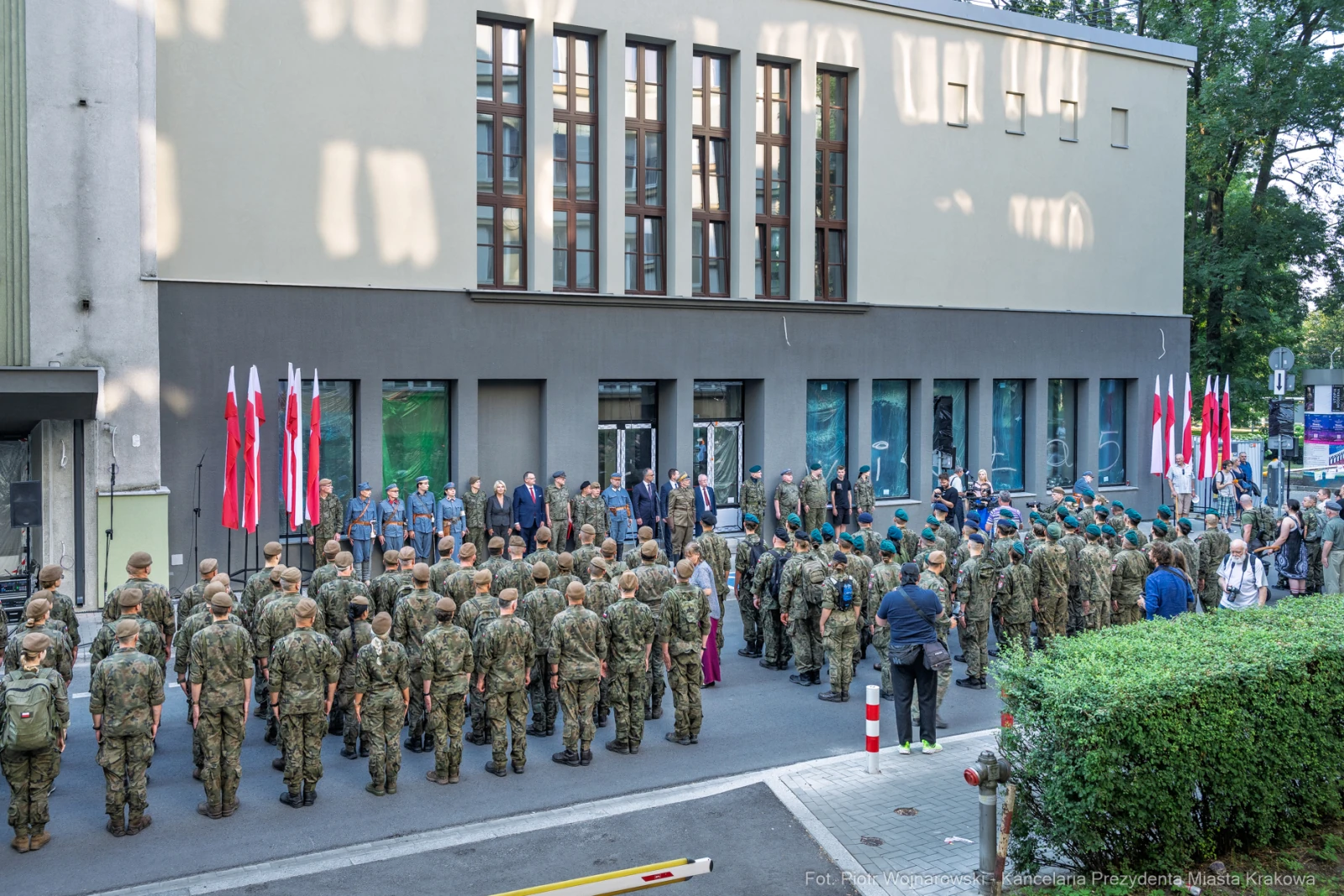Uroczystość z udziałem żołnierzy i flag narodowych przed budynkiem.  Autor: Piotr Wojnarowski