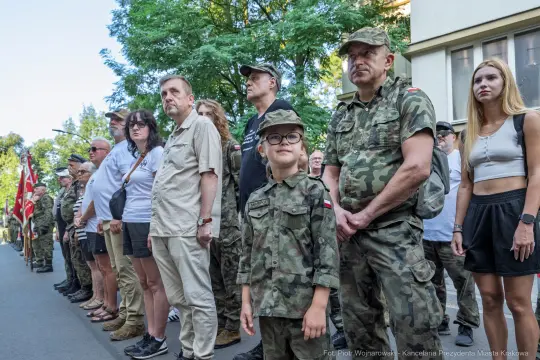 Grupa ludzi w mundurach wojskowych oraz cywilnych, w tym dziecko, podczas uroczystości.
