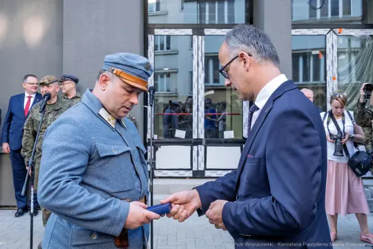 Wręczenie odznaczenia w uroczystości z udziałem wojskowych i przedstawicieli władz.