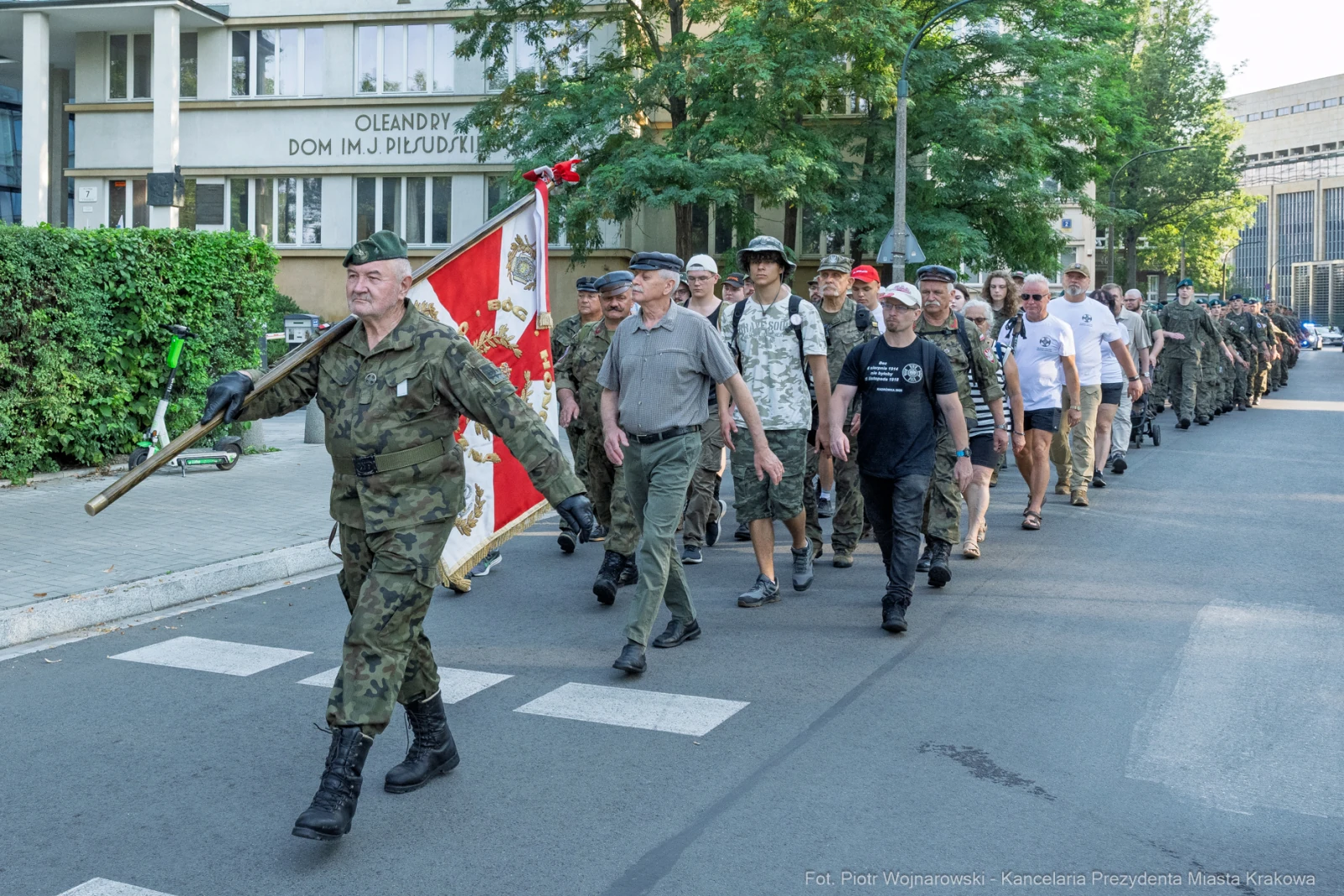 Marsz weteranów z flagą, uczestnicy w mundurach i koszulkach, ulica w Krakowie.  Autor: Piotr Wojnarowski