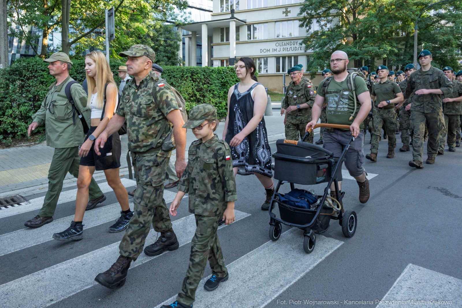 Grupa osób w mundurach wojskowych i cywilnych przechodzi przez ulicę.  Autor: Piotr Wojnarowski