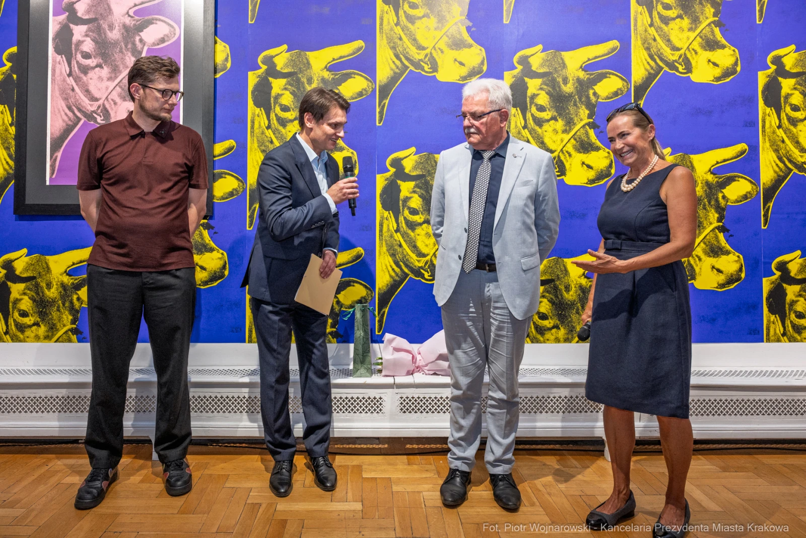 Wystąpienie mężczyzny w garniturze podczas wydarzenia artystycznego z osobami w tle.  Autor: Piotr Wojnarowski
