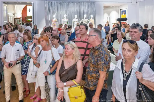 Grupa ludzi na wydarzeniu, różnorodne reakcje i styl ubioru.