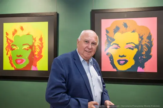 Mężczyzna stoi przed obrazami przedstawiającymi Marilyn Monroe w intensywnych kolorach.