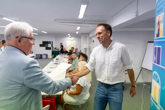Mężczyźni podają sobie ręce podczas spotkania w sali konferencyjnej.