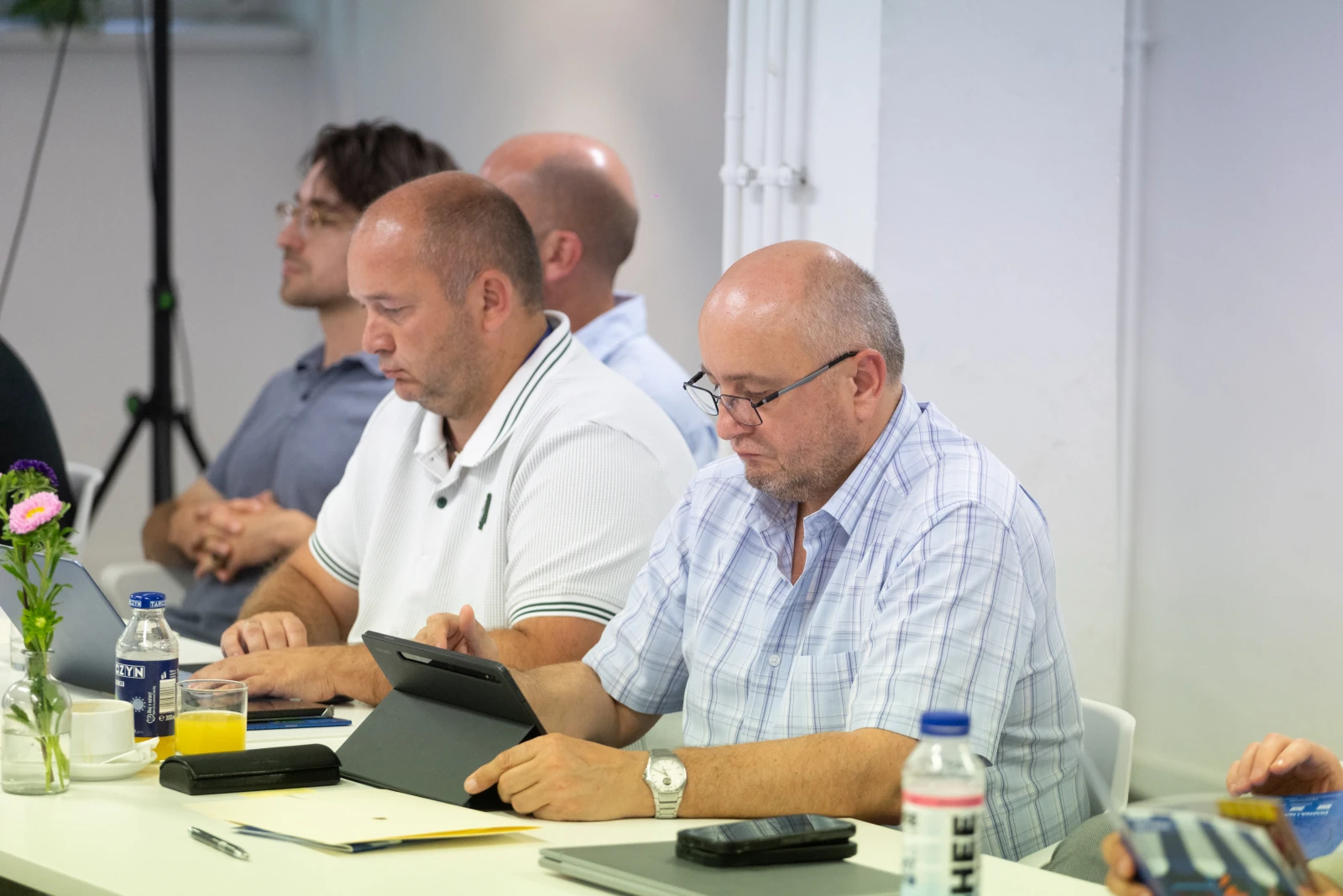 Grupa mężczyzn uczestniczy w spotkaniu, niektórzy korzystają z tabletów.  Autor: Bogusław Świerzowski