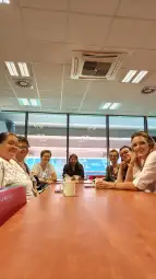Grupa kobiet siedzących przy stole w jasnym pomieszczeniu.
