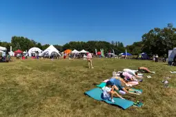 Ludzie relaksujący się na trawie podczas festiwalu na świeżym powietrzu.