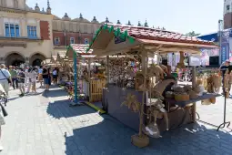 Stragany z rękodziełem na festiwalu, tłum ludzi, słoneczna pogoda.
