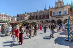 Tłum ludzi spacerujących po rynku, stragany z rękodziełem i dekoracjami. Słoneczna pogoda.