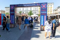 Targi sztuki ludowej z tłumem ludzi i straganami w tle.