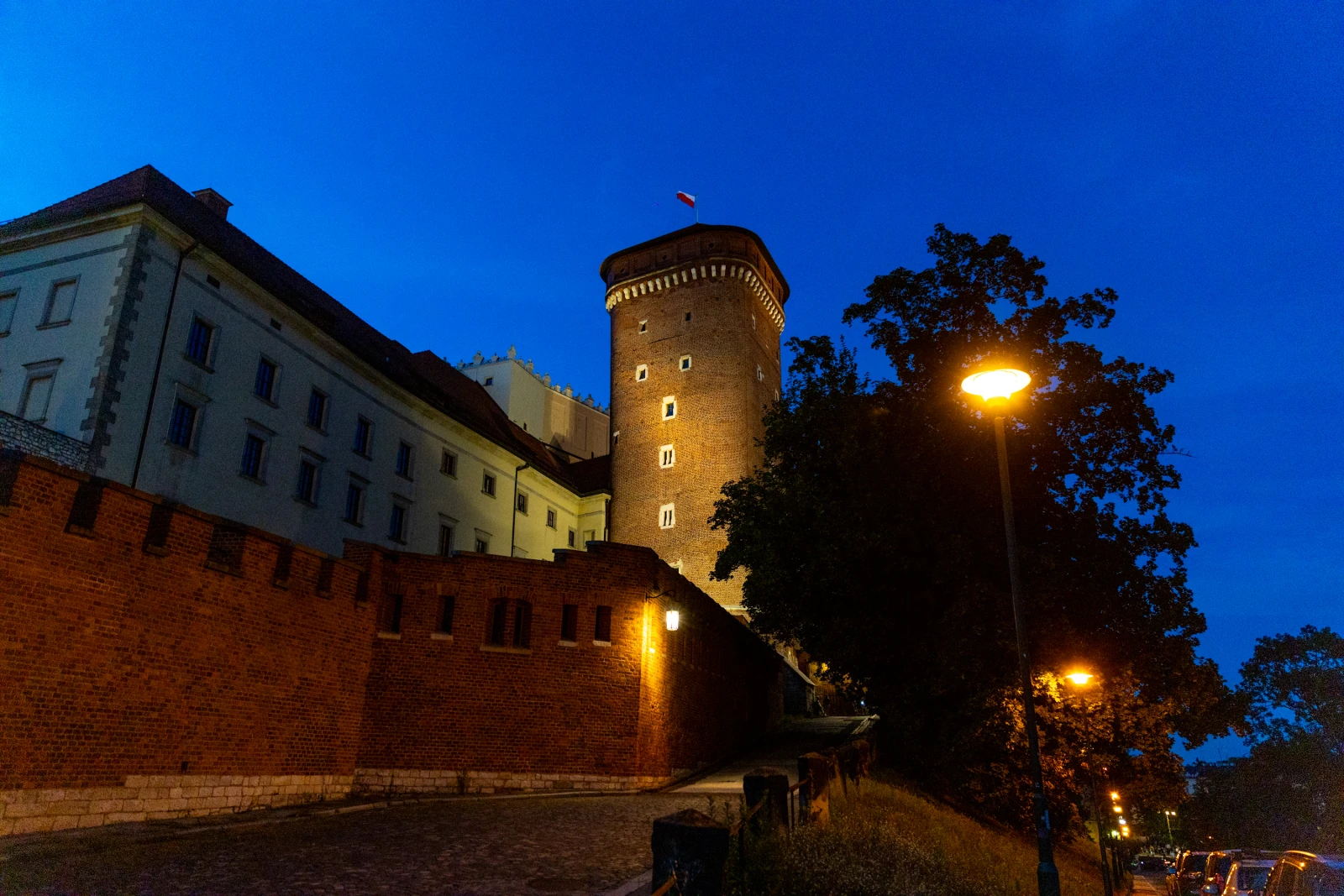 Zamek na Wawelu oświetlony w nocy, z widoczną wieżą i flagą.  Autor: Bogusław Świerzowski