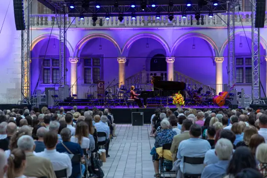 Koncert fortepianowy na świeżym powietrzu z publicznością w tle.