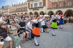 Tancerki w tradycyjnych strojach ludowych występują przed tłumem na rynku.