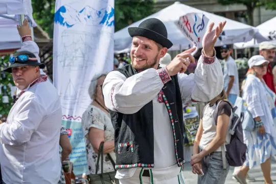 Mężczyzna w tradycyjnym stroju ludowym tańczy i gestykuluje podczas festiwalu.