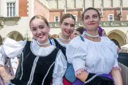 Trzy uśmiechnięte kobiety w tradycyjnych strojach ludowych.