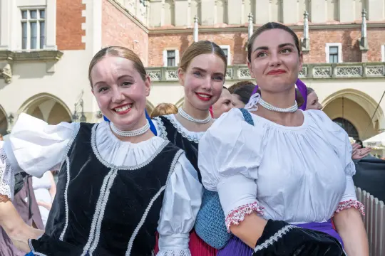 Trzy uśmiechnięte kobiety w tradycyjnych strojach ludowych.