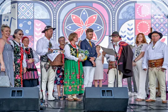 Grupa ludzi w tradycyjnych strojach ludowych podczas wystąpienia na scenie.