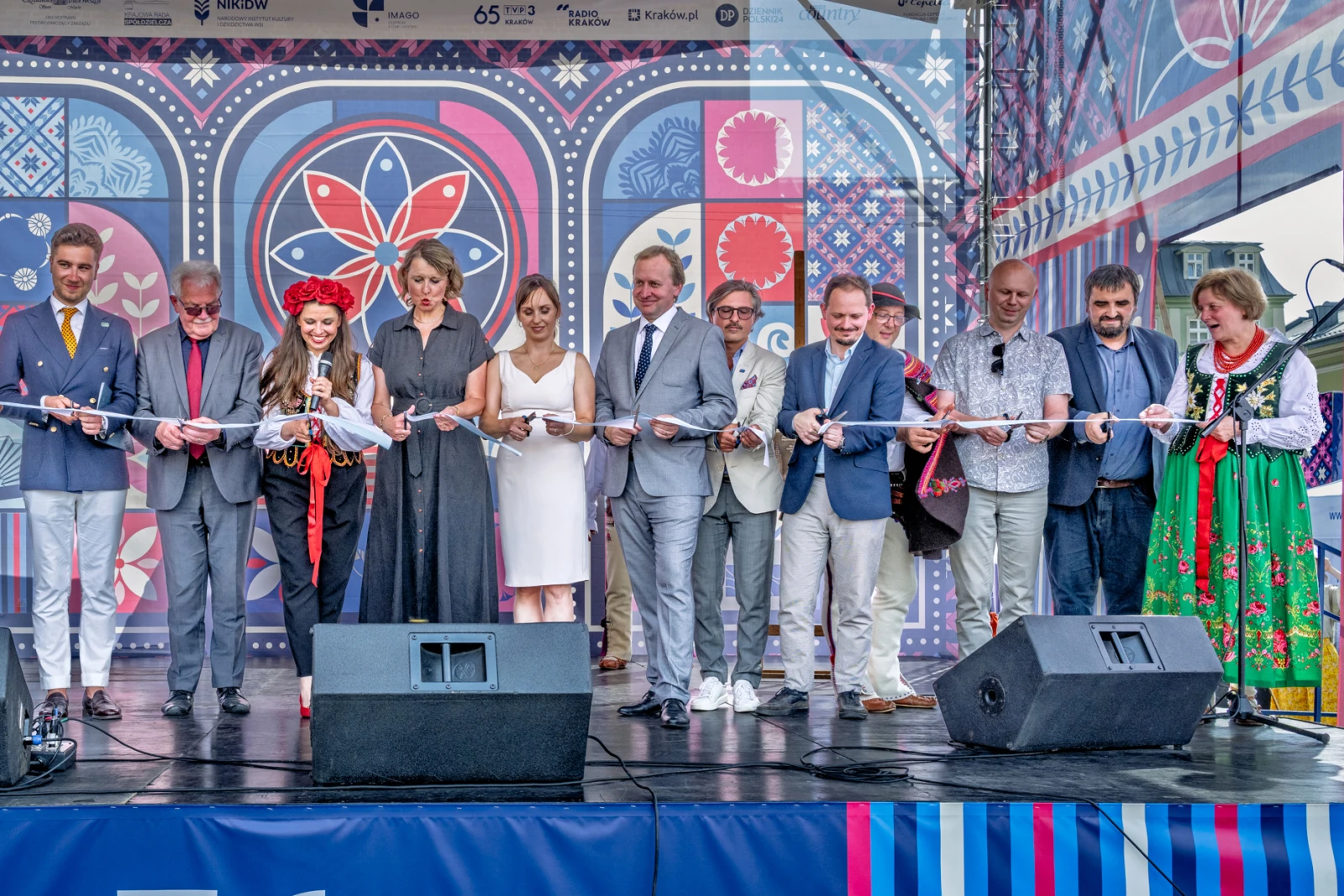 Otwarcie wydarzenia z uczestnikami na scenie, trzymającymi w rękach wstęgę.  Autor: Piotr Wojnarowski