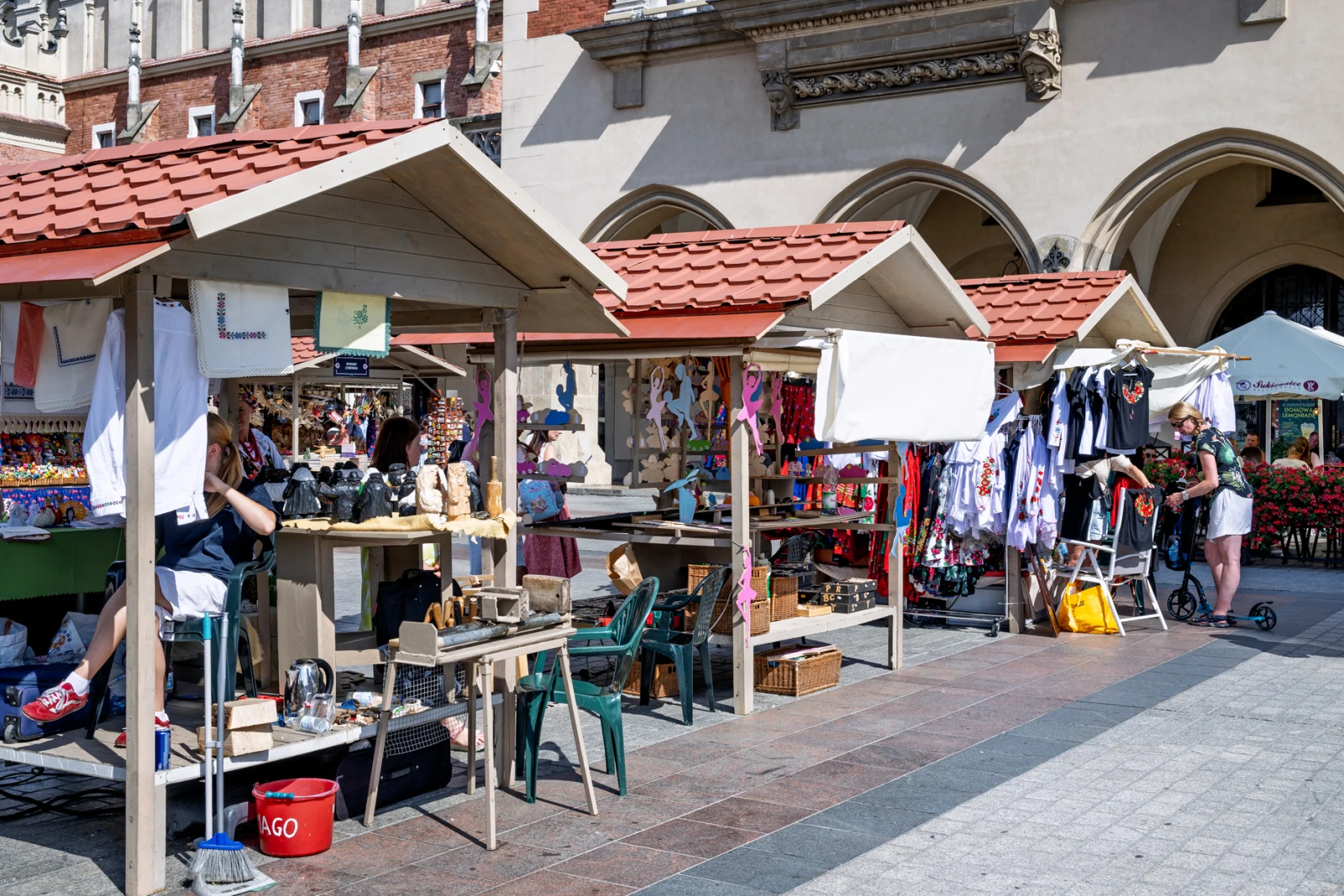 Stragany z rękodziełem i ubraniami na rynku, ludzie przeglądający towary.  Autor: Piotr Wojnarowski